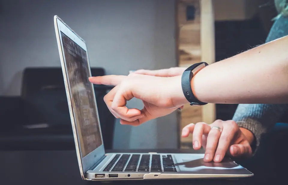 Handen bij een laptop tijdens uitleg, persoonlijke opvolging na het eerste contact