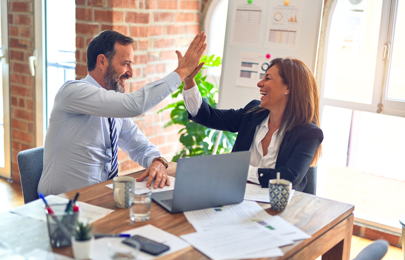 Twee mensen geven elkaar een high five aan een bureau nadat een websitefout is opgelost